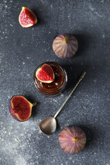 Wall Mural - Jar of sweet fig jam with spoon on grey grunge background