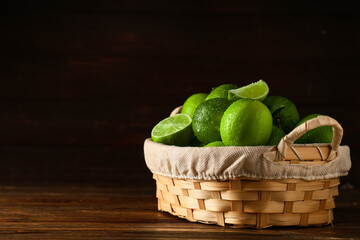 Wall Mural - Wicker basket with fresh ripe limes on wooden background