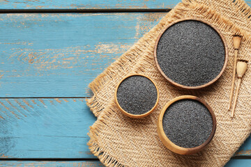 Wall Mural - Bowls with poppy seeds on blue wooden background