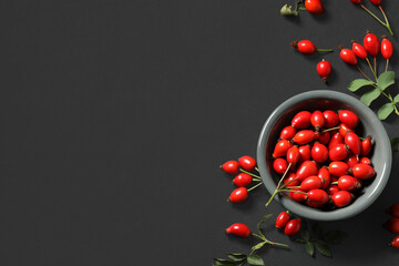Wall Mural - Bowl with fresh rose hip berries on black background