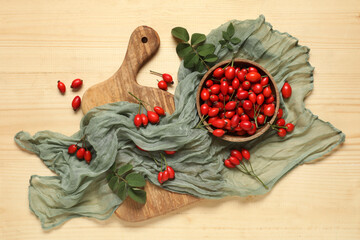 Wall Mural - Bowl and cutting board with fresh rose hip berries on wooden background