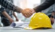© Ivan - Construction Worker Team Shaking Hands Over Yellow Safety Helmet On Office Desk: Starting A New Project Contract At Construction Site With Partners And Contractors