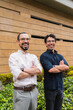 © pablo - Two twin brothers with crossed arms smiling at the camera outdoors