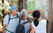 © luciano - Group of senior friends in outdoors excursion looking at the map looking for right direction in the mountain area