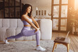 © Prostock-studio - A young woman performs lunges in her cozy living room. She follows an online workout displayed on her laptop, enjoying the warm light coming through the windows.