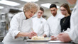 © SolaruS - Chef decorating cake with students observing in a professional kitchen. Shows expertise, training, culinary arts and food preparation. Ideal for education, hospitality, and food industry concepts.