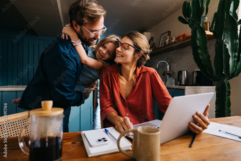 Photo Stock Brief family bonding moment as mom works on laptop at ...