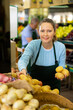 © JackF - Positive middle-aged saleswoman setting out potatoes on food stall in grocery store