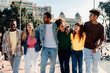 © Xavier Lorenzo - Group of diverse millennial friends walking together through Catalunya Square in Barcelona, enjoying a sunny day and sharing laughter in the heart of the city. Friendship and urban lifestyle concept.