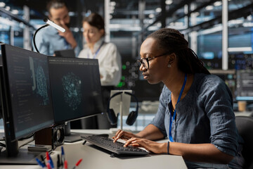 Focused admin in data center using AI powered tech to run simulations. Worker coding cognitive computing algorithms to extract insights from data and automate equipment racks