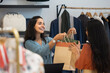 © fizkes - Happy Latin fashion outlet cashier giving shopping bags to customer