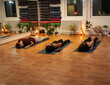 © phoenix021 - Group of three people, two women and young man practicing yoga indoors, resting on yoga mat, with forehead on mat