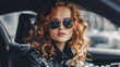 © Daria - Fashion-forward young woman with curly red hair and stylish sunglasses sitting in a modern car, embodying confidence and elegance in urban driving fashion