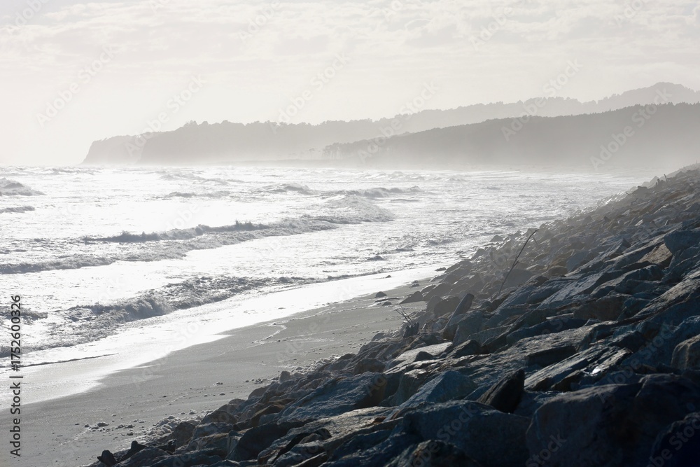 Waves crash on rocky Bruce Bay shore under cloudy sky, South Island ...