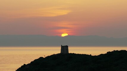 Wall Mural - San Macario island and tower with setting sun in background, Pula, Sardinia, Italy. Aerial drone lateral view