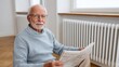 © iuricazac - Older man sitting in a living room, reading newspaper.