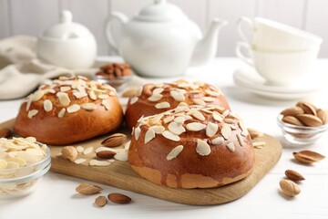 Wall Mural - Tasty roll buns with almond flakes, nuts and tea set on white wooden table, closeup