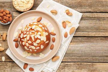 Wall Mural - Tasty roll bun with almond flakes and nuts on wooden table, flat lay. Space for text
