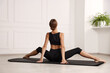 © New Africa - Woman doing gymnastic exercise on fitness mat indoors, back view