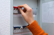 © Андрей Журавлев - Woman hand turning on a red circuit breaker switch in an electrical panel. Home fuse box for electricity control and safety concept.