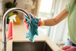© Davor - Young adult cleaning kitchen faucet