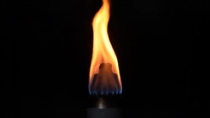 Sticker - a single, vibrant torch flame dances in a dark, mysterious setting, captured in a steady close-up wi
