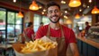 © Pete - Happy young man gives takeaway order with french fries at fast food restaurant. Smiling waiter in apron serves customer at cafe counter. Employee works in eatery providing friendly service. Barista