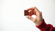 © Pete - Woman hand holds small chocolate candy on stick. Female with white manicure offers sweet dessert. Girl in red sweater presents single tasty chocolate bite. Concept of craving portion control with