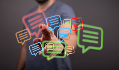 A man's hand reaches out to touch glowing digital speech bubbles, symbolizing communication and interaction in a modern digital world.