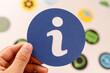 © vegefox.com - A hand holds a blue circle with an information symbol. The image also features other colorful circles in the background. Perfect for concepts of