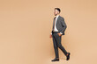 © ViDi Studio - Full body side profile view young fun successful employee business man corporate lawyer wear classic formal grey suit shirt tie work in office walking going isolated on plain beige background studio