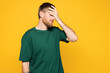 © ViDi Studio - Young shocked Caucasian man he wear green t-shirt casual clothes put hand on face facepalm epic fail mistaken omg gesture isolated on plain yellow orange background studio portrait. Lifestyle concept.
