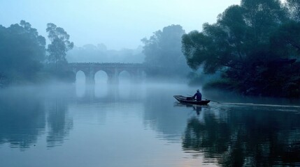 Wall Mural - early morning river, enveloped in thin mist, soft blue dawn sky, gentle sunlight piercing through fog with golden rays, tranquil waters reflecting light, slow-moving small traditional boat
