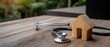 © pvl0707 - Wooden house model placed next to a stethoscope on a wooden table in a serene outdoor setting representing home health care concepts