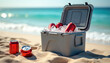 © miss irine - Portable cooler box with ice cubes and red soda cans on a sandy beach. Cold refreshing drinks for a summer party by the blue sea. Chilled beverages for a sunny vacation picnic.
