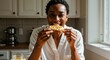 © NN AI - Happy Black woman eating toast for breakfast in sunlit kitchen. Young female enjoying healthy morning snack at home. Simple pleasures and wellness lifestyle