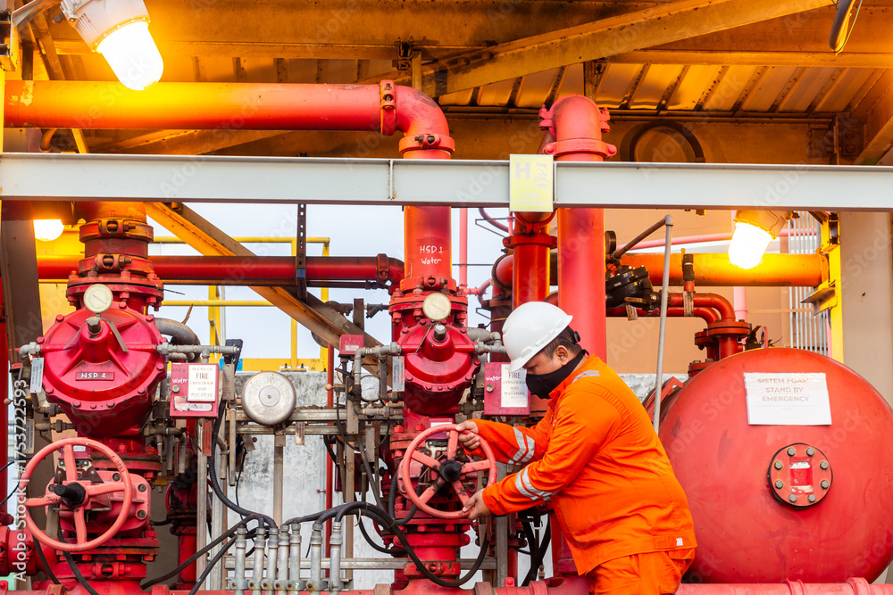 Industrial worker operates a red valve on a fire suppression system for ...