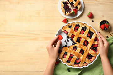 Wall Mural - Female hands and tasty berry pies on light wooden background
