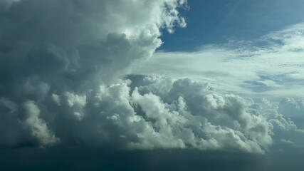 Wall Mural - A peaceful flight experience flying near a massive cumulonimbus storm cloud, in a turbulent bright blue sky as seen by the pilot from a jet cockpit.