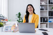 © David - Asian woman holding paper and using laptop computer making business report working online sitting at workplace office. successful business accounting and entrepreneurship.