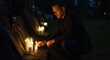 © NN AI - Man lighting remembrance candle at grave in cemetery at night. Grieving person paying tribute to loved one. Mourning and loss concept