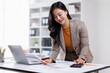 © David - Cheerful business lady working on laptop in office, Young attractive business asian woman working on her project with laptop computer in modern office room.