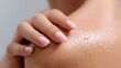© Starmarpro - Close up shot of fair skin, showing a woman's hand with glossy pink nails gently touching her shoulder covered with water droplets.