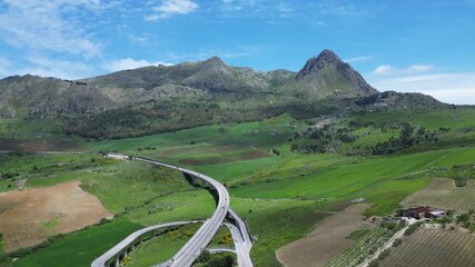 Wall Mural - Aerial drone footage of the Sicilian countryside: winding roads, green fields, and mountain landscapes under bright Mediterranean light. Ideal for travel, nature, and adventure projects.
