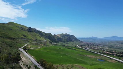 Wall Mural - Aerial drone footage of the Sicilian countryside: winding roads, green fields, and mountain landscapes under bright Mediterranean light. Ideal for travel, nature, and adventure projects.