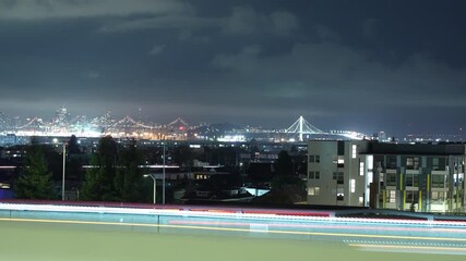 Wall Mural - The time-lapse captures the steady motion of cars along the I-24 and I-580 freeways in downtown Oakland as twilight fades into night and city lights begin to glow.