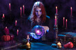 © TSViPhoto - Witch casts a spell with magic Crystal ball for predictions fortune-telling. Young woman, magician girl with red hair, dressed in Halloween clothes and conical hat in a room with candles