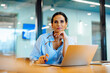 © (JLco) Julia Amaral - Professional woman sitting at desk with laptop in a bright office setting