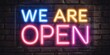 © Oleksandr - We Are Open Neon. Neon Sign on Brick Wall for Business Advertising