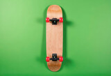 Top view of upside-down skateboard with red wheels on green background